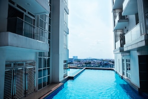 A modern building with a swimming pool, large windows, and a view of a cityscape. - KSL D'Esplanade Residence by Immaculate (Johor Bahru)