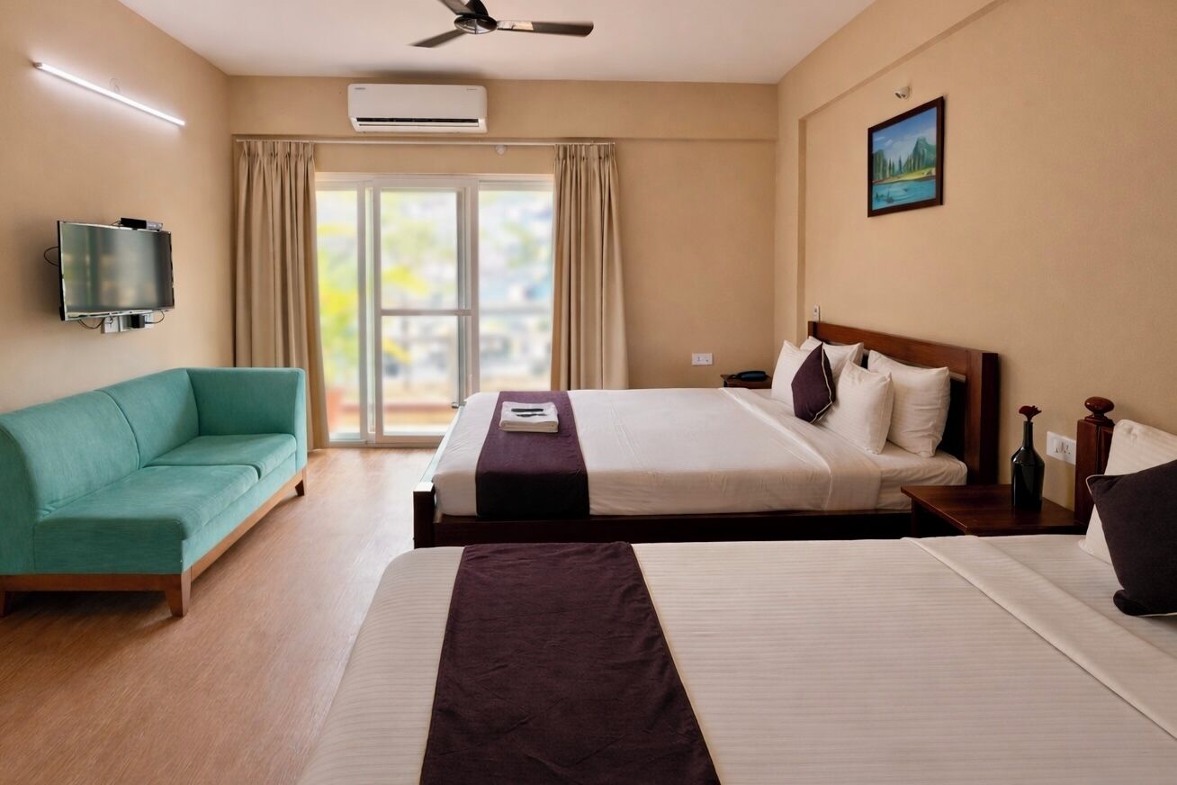 Una habitación de hotel con dos camas, televisión, aire acondicionado y un cuadro en la pared.