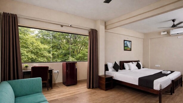 Een hotelkamer met een bed, een bureau, een stoel, een kledingkast en een raam met gordijnen.
