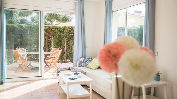 A modern living room with a sofa, coffee table, and a dining area with chairs and a table.