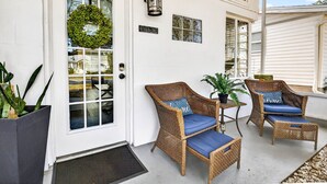 A white house exterior with a front door, a number plaque, a lantern, and wicker furniture with cushions. - New Port Richey Downtown 🌴 (New Port Richey)