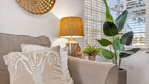 A beige sofa with a decorative pillow, a woven lamp, and a large plant in a woven pot. - New Port Richey Downtown 🌴 (New Port Richey)