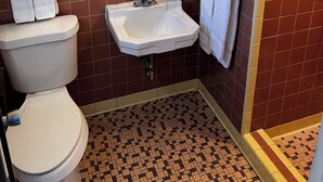 A bathroom with a white toilet, a sink with a mirror above it, and a shower area.
