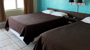 A hotel room with two beds, a ceiling fan, a window with curtains, a wall-mounted lamp, and a painting.