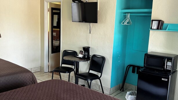 A hotel room with a bed, a desk with a chair, a television, a microwave, and a ceiling fan.