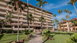 A multi-story hotel with a central courtyard, palm trees, and a clear blue sky. - Marina Sol Condominiums (Cabo San Lucas)