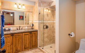 A bathroom with a glass-enclosed shower, a wooden vanity with a sink, and a large mirror above the vanity. - Marina Sol Condominiums (Cabo San Lucas)