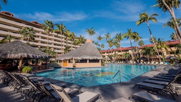 A resort pool area with lounge chairs, a thatched-roof hut, and palm trees. - Marina Sol Condominiums (Cabo San Lucas)