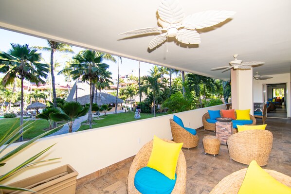 A resort lounge with wicker furniture, a pool view, and ceiling fans. - Marina Sol Condominiums (Cabo San Lucas)
