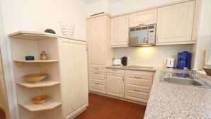 A kitchen with light wooden cabinets, a granite countertop, and a stainless steel sink.