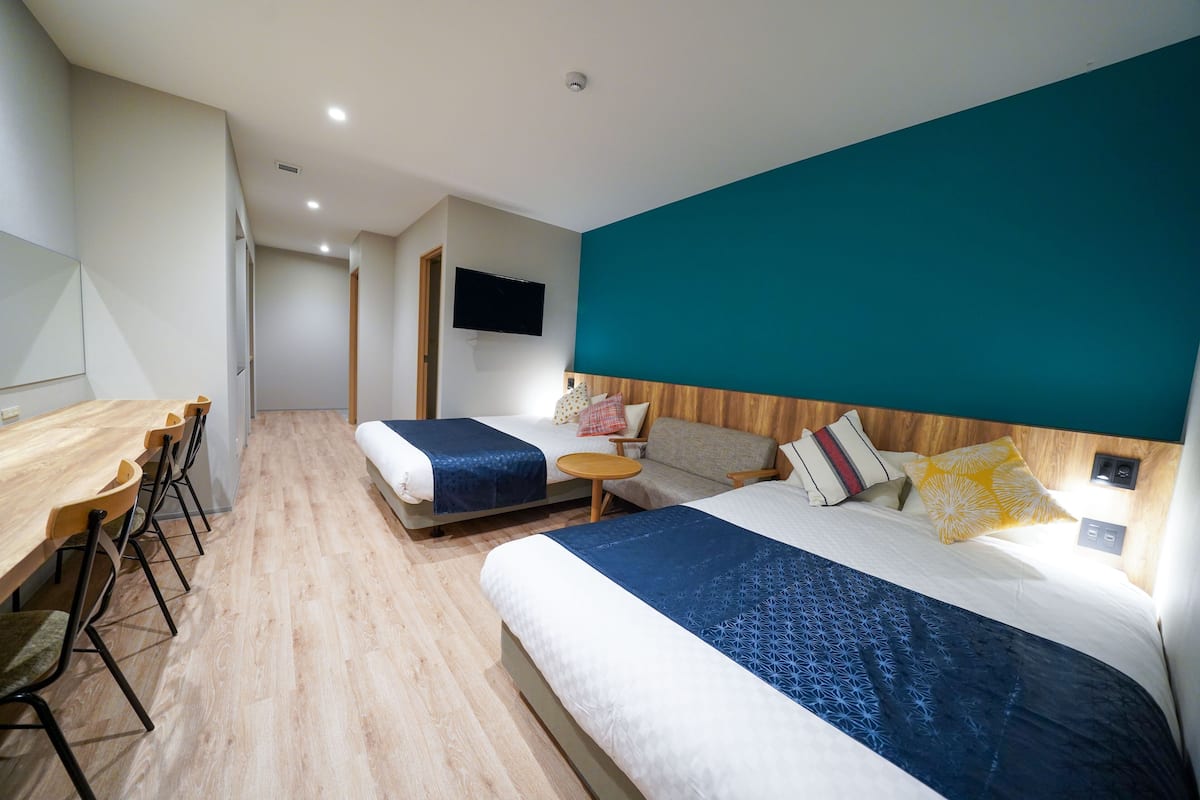 A hotel room with two beds, a desk, and a TV.