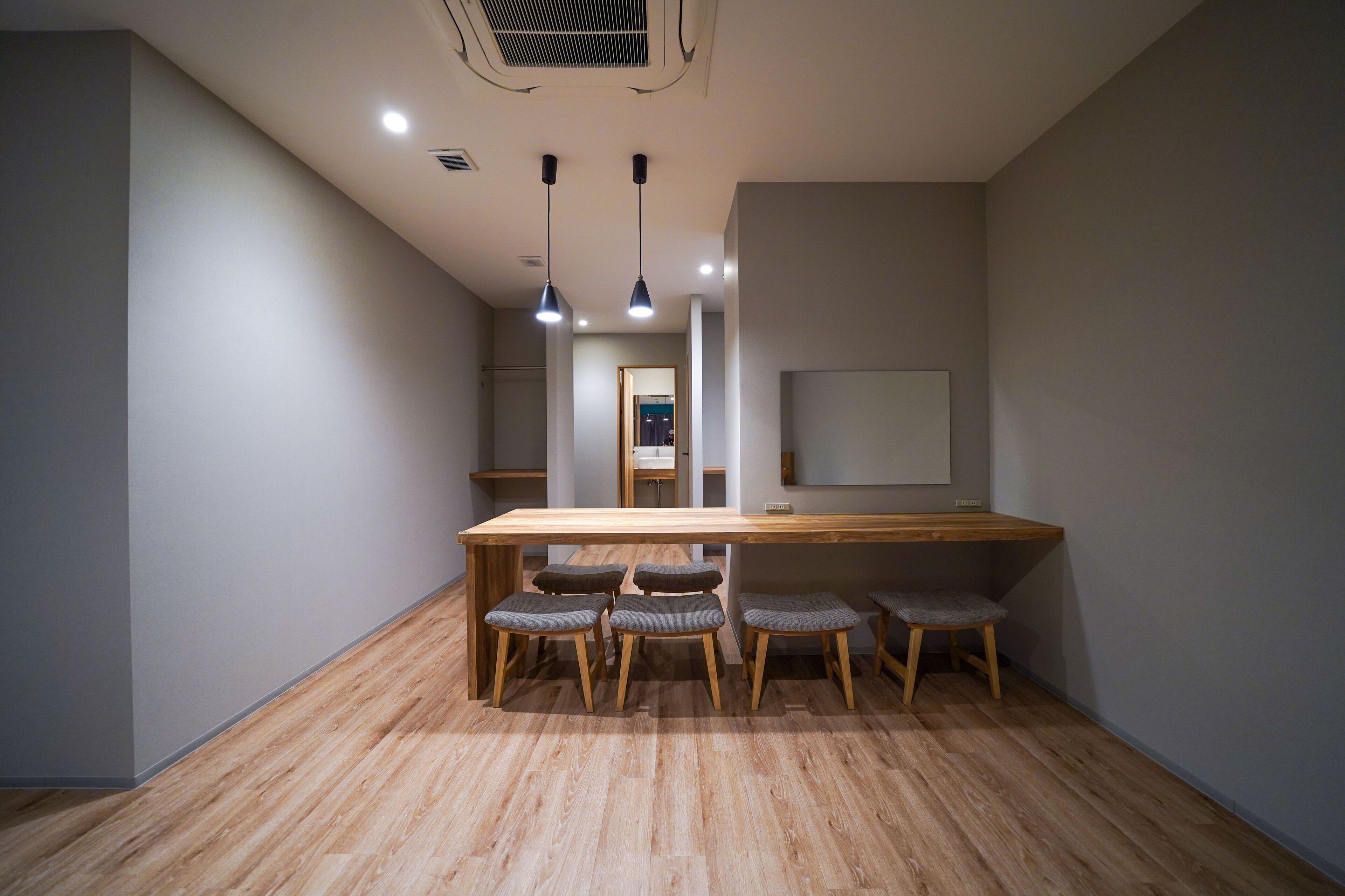 A modern interior with a wooden table and six chairs, a large mirror, and recessed ceiling lighting.