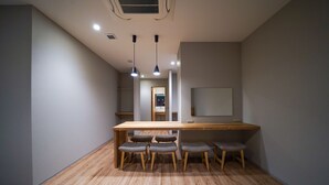 Um interior moderno com mesa de madeira e seis cadeiras, um espelho grande e iluminação embutida no teto.