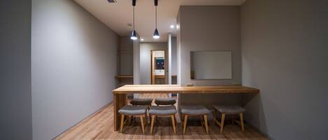 A modern interior with a wooden table and six chairs, a large mirror, and recessed ceiling lighting.