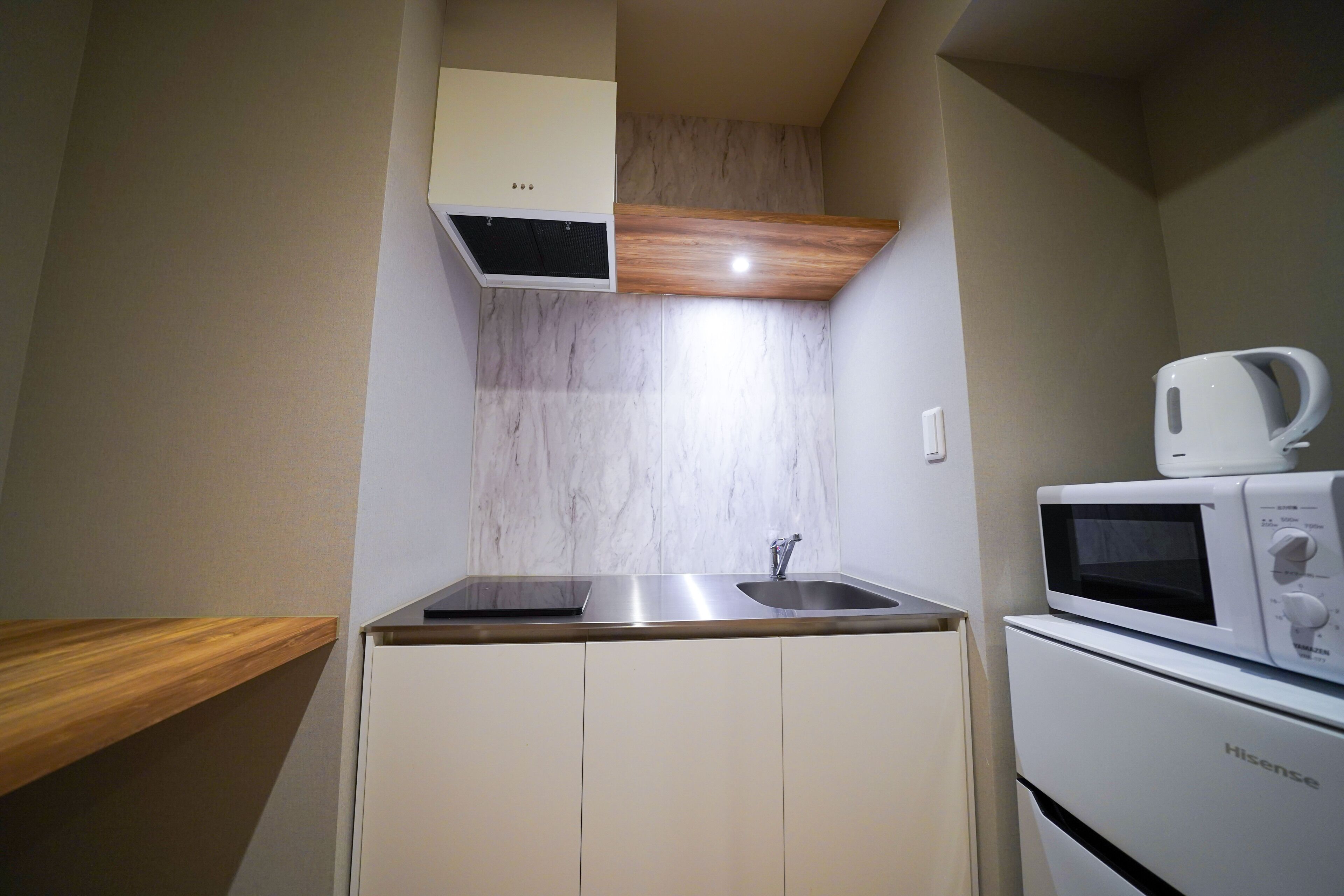A compact kitchen with a microwave, sink, and built-in oven.