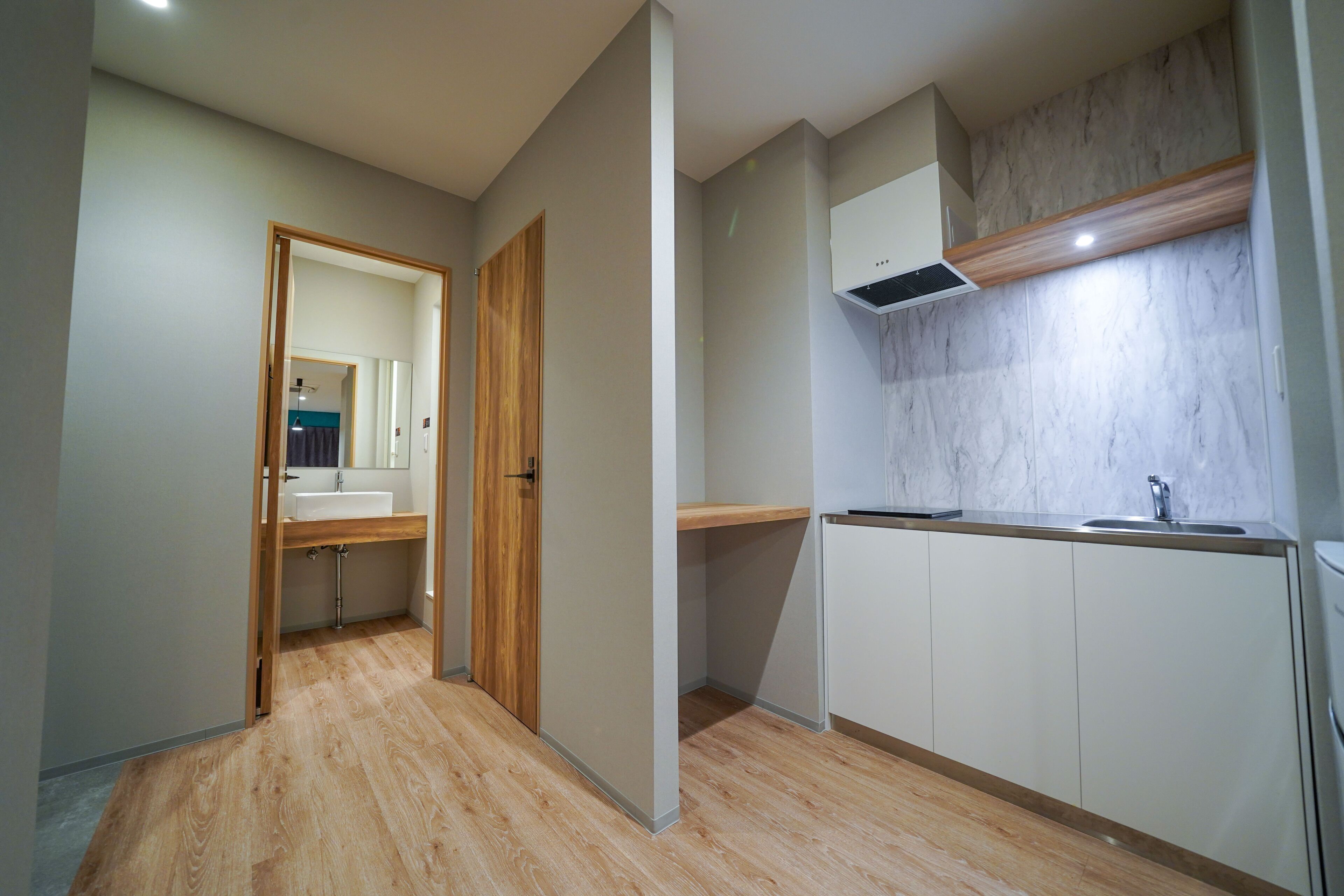 A modern kitchen with a wooden floor, white cabinets, and a marble backsplash.