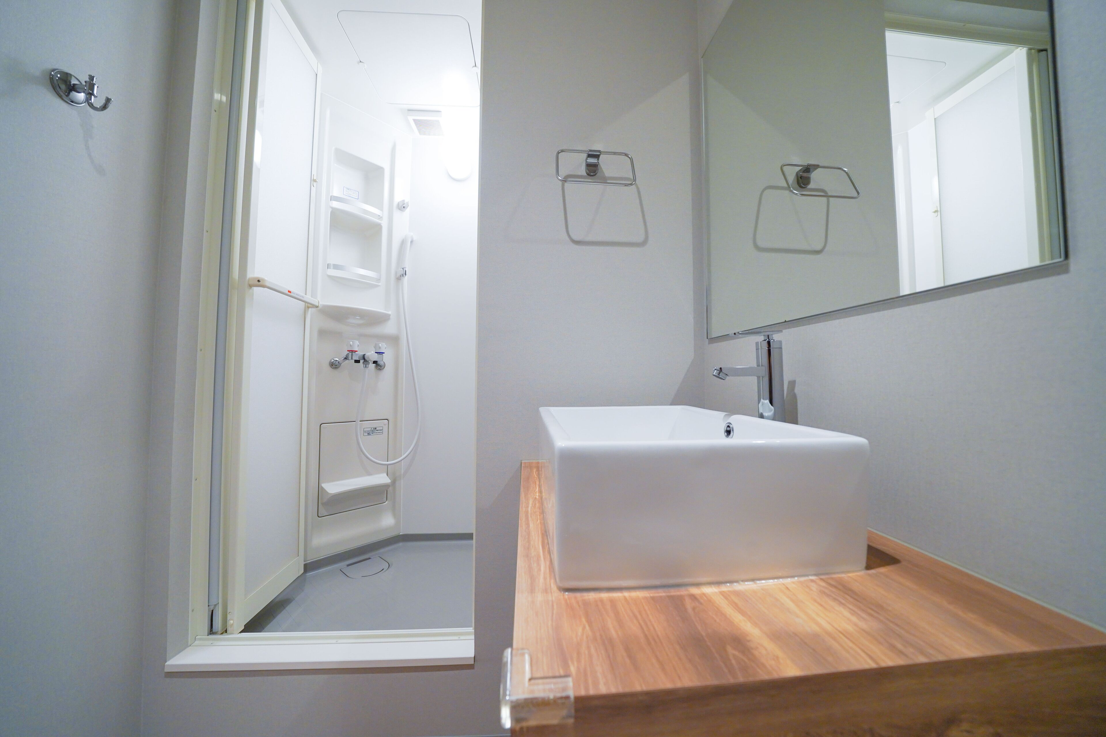 A bathroom with a white sink, wooden countertop, and a large mirror.