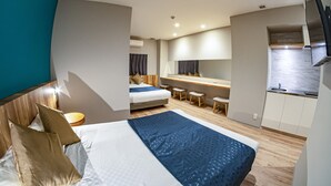Quarto de hotel moderno com uma cama grande, uma escrivaninha e uma cozinha compacta.