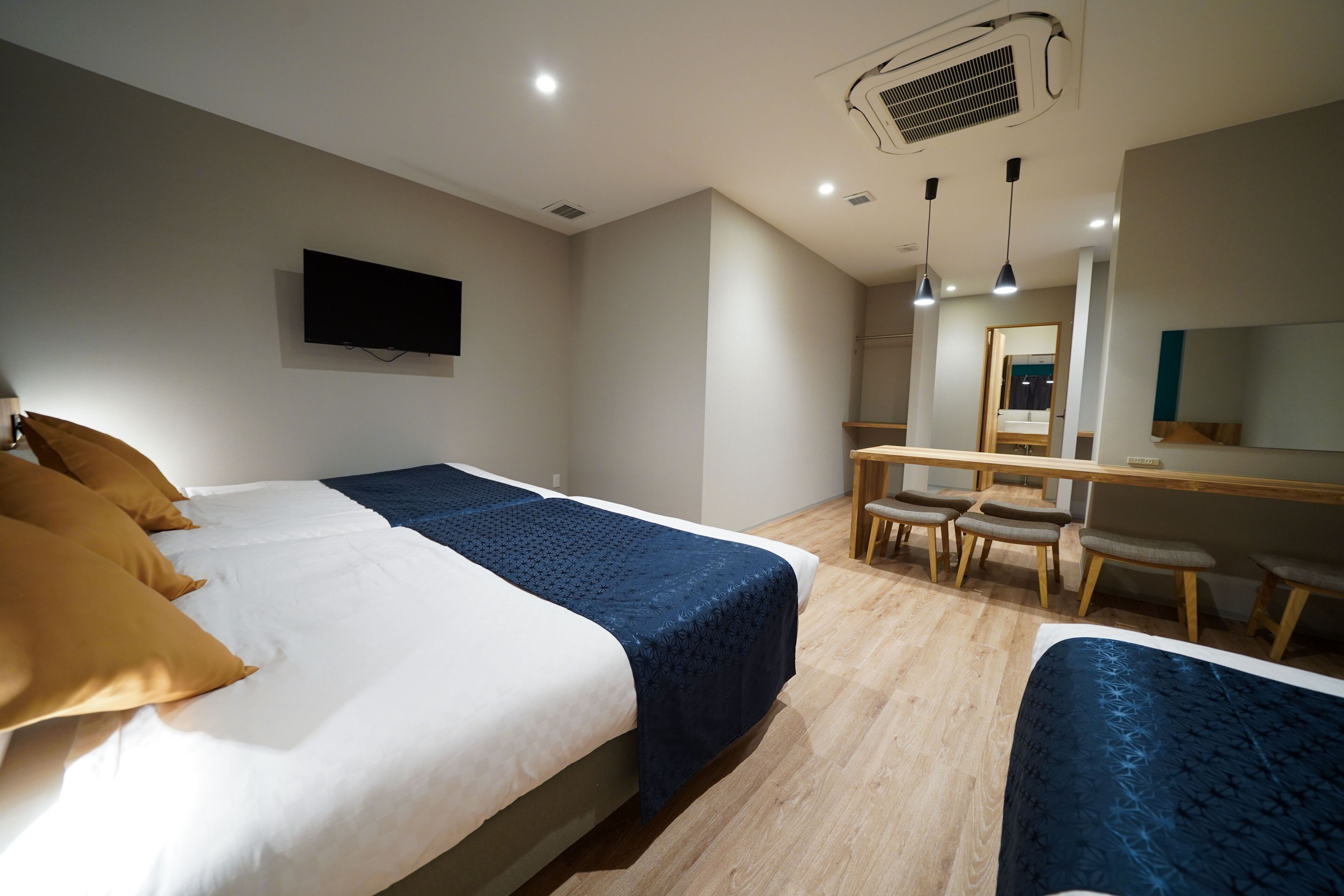 A hotel room with two beds, a desk, a chair, a TV, and a mirror.