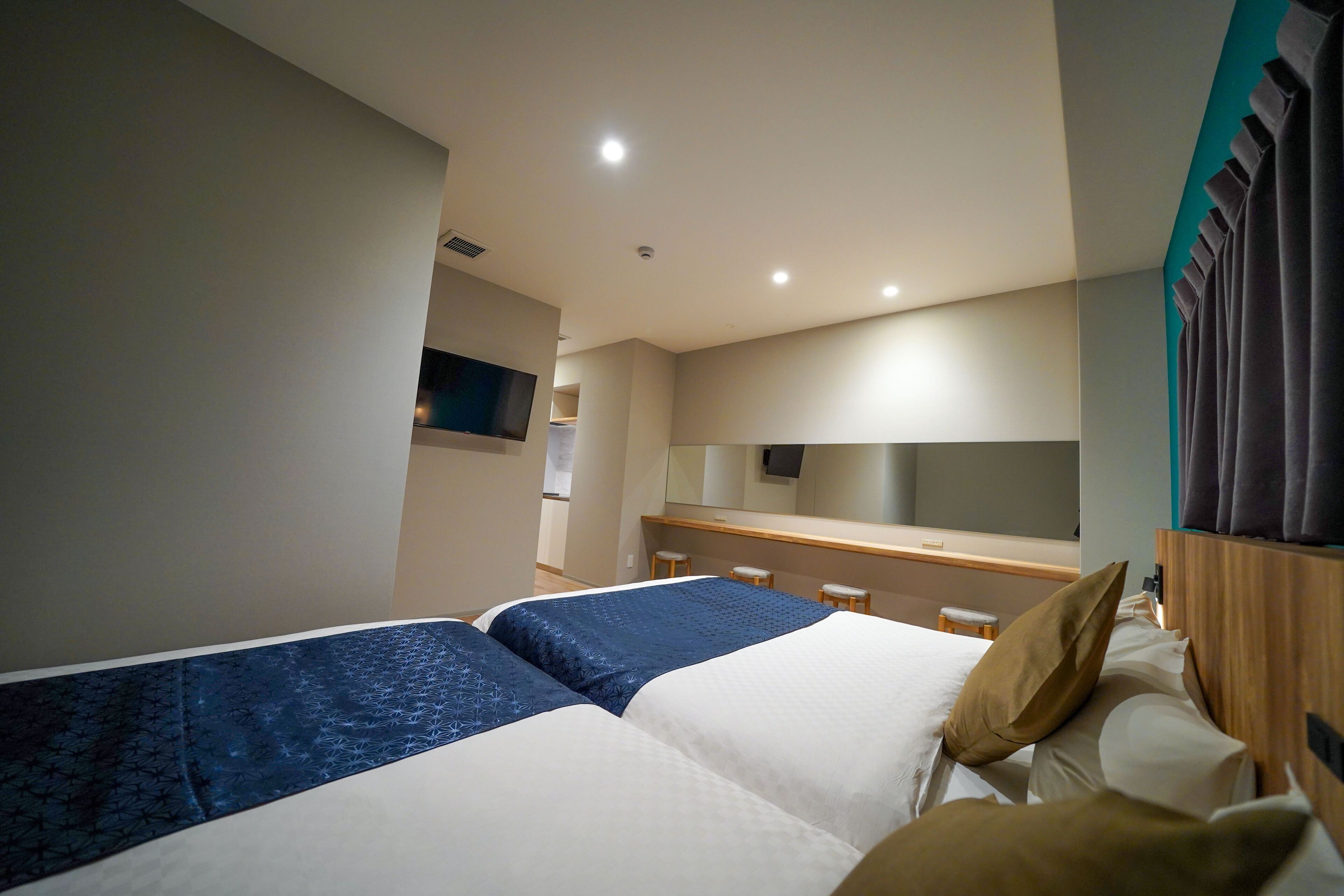 Ein Hotelzimmer mit zwei Betten, einer kleinen Sitzecke, einem Fernseher und einem Spiegel.