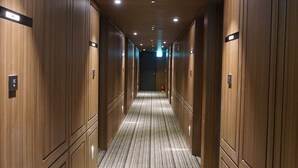 A hotel hallway with wooden paneling, carpeted floors, and recessed lighting. - Yeoubi Hotel (Changwon)