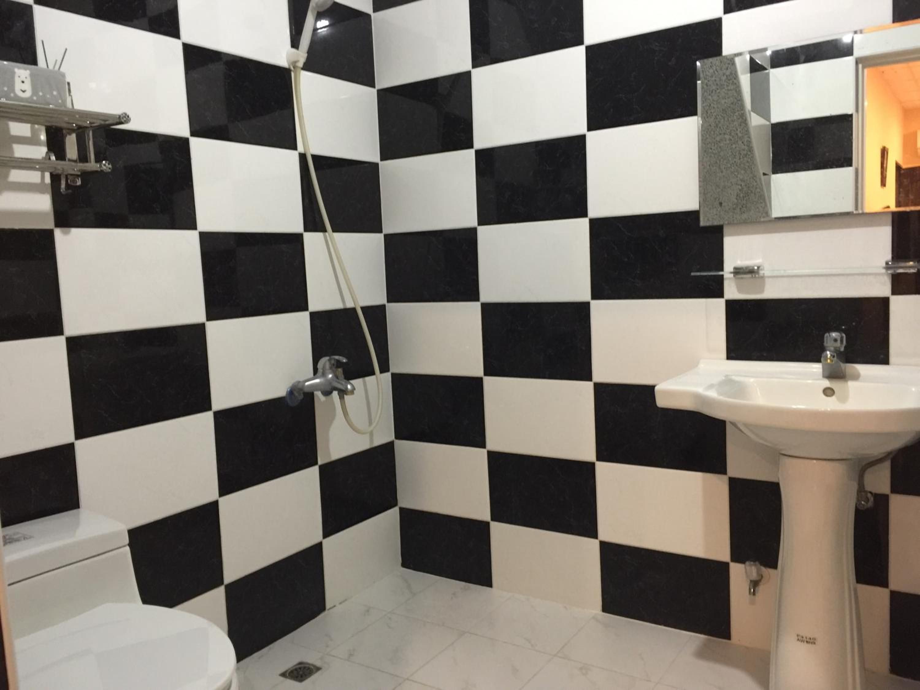 A bathroom with black and white checkered tiles, a white sink, and a shower.