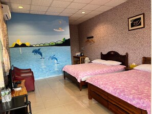 A hotel room with two beds, a mural of dolphins, a wooden headboard, and a small table with a fan. - Golden Flower B&B (Yuli)