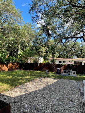 A backyard with a wooden fence, a gravel area, and a patio with outdoor furniture.