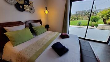 Habitación de hotel con cama, almohadas, lámpara de noche, vistas al exterior e iluminación en el techo.