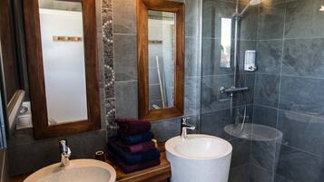 Een moderne badkamer met twee grote wasbakken, een douche en een bad.