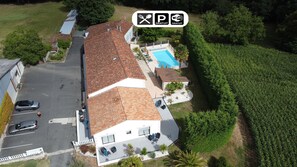 Vista aerea di una casa con piscina, giardino recintato e area di parcheggio.
