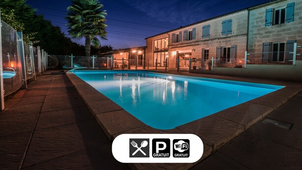 A swimming pool with a tiled deck, a palm tree, and buildings with blue shutters. - Les Cuves (Chaniers)