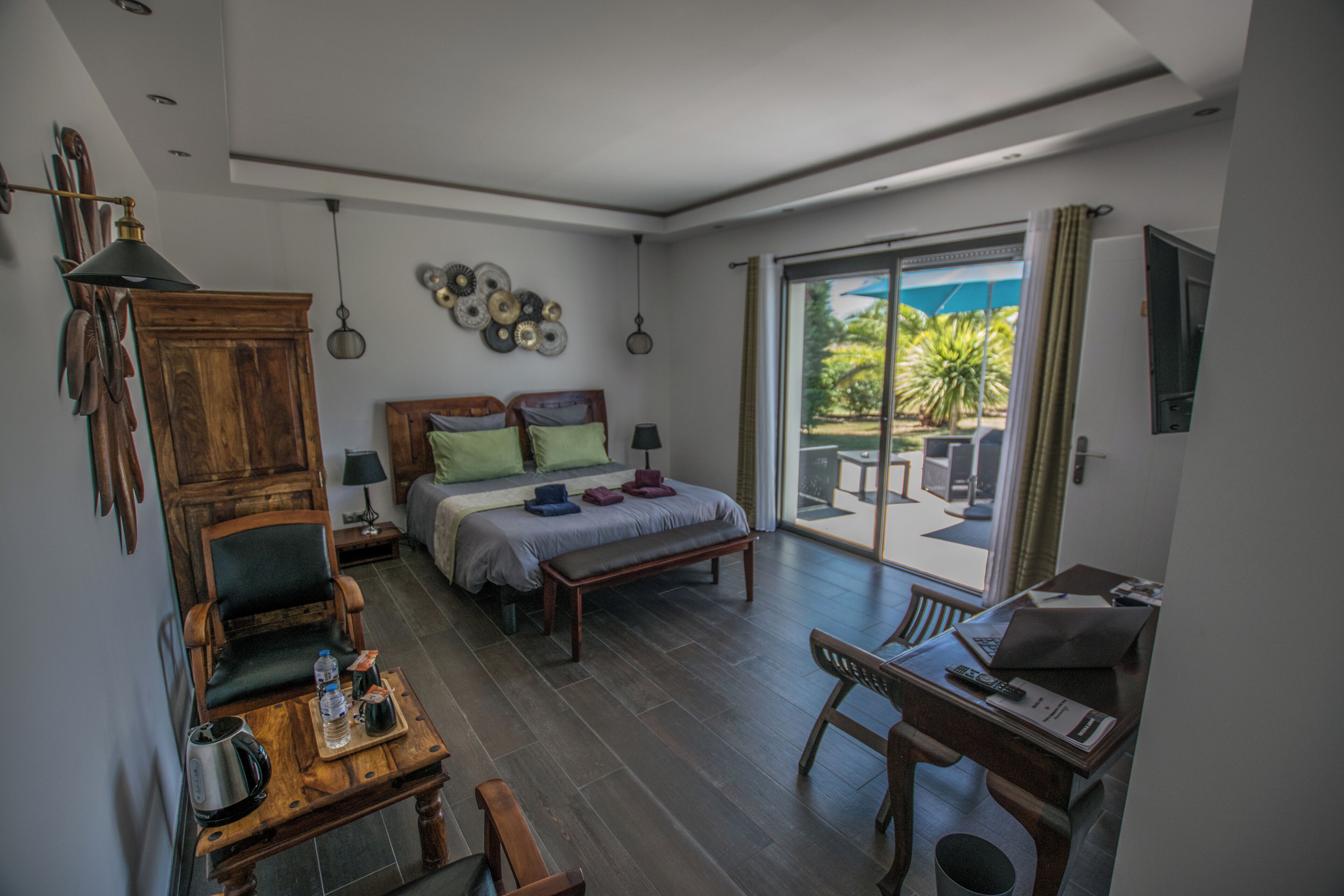 A bedroom with a bed, bedside tables, a desk, a chair, and a view of the outdoors.