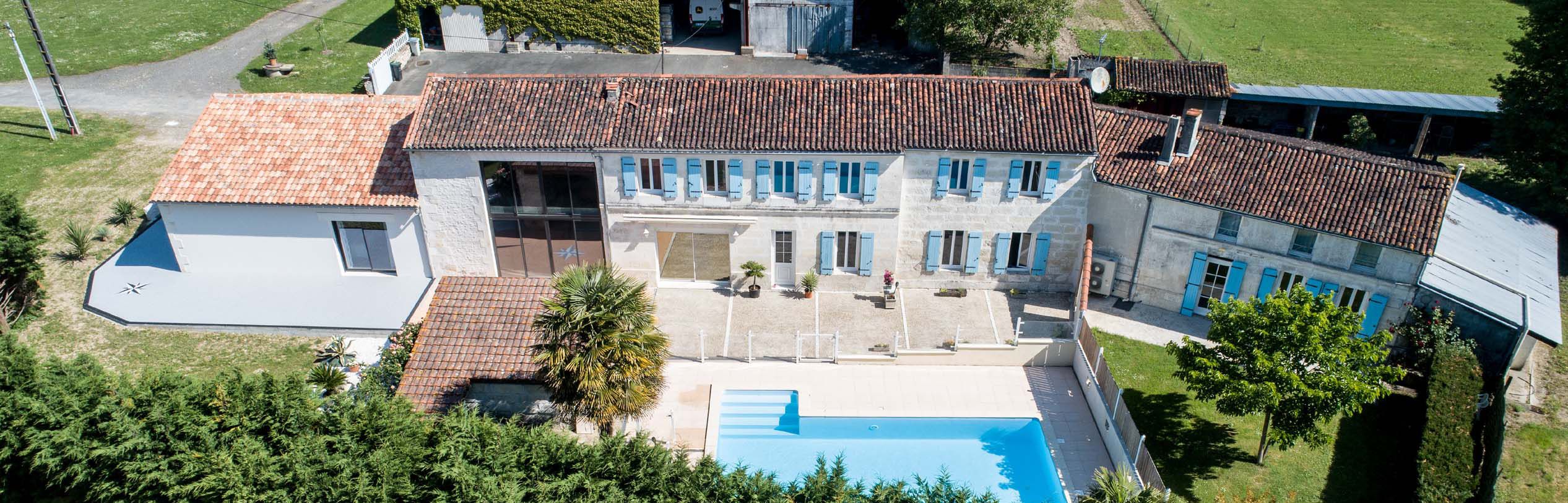 A large building with a swimming pool, multiple windows, and a tiled roof.