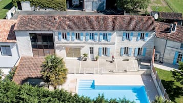 A large building with a swimming pool, multiple windows, and a tiled roof.