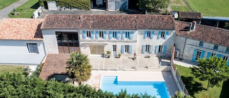 A large building with a swimming pool, multiple windows, and a tiled roof.