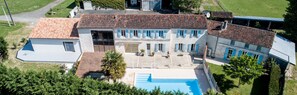 A large building with a swimming pool, multiple windows, and a tiled roof. - Les Cuves (Chaniers)