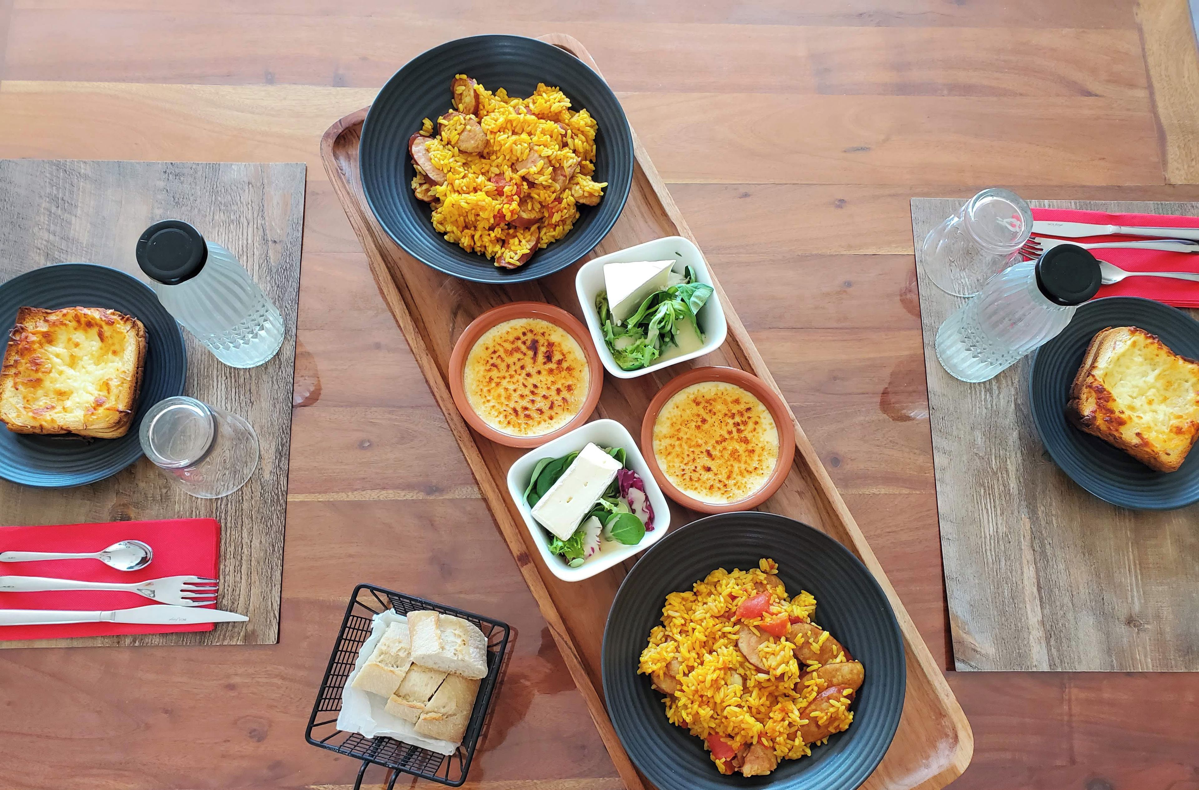 Een houten eettafel met diverse gerechten, waaronder rijst, brood en salades.