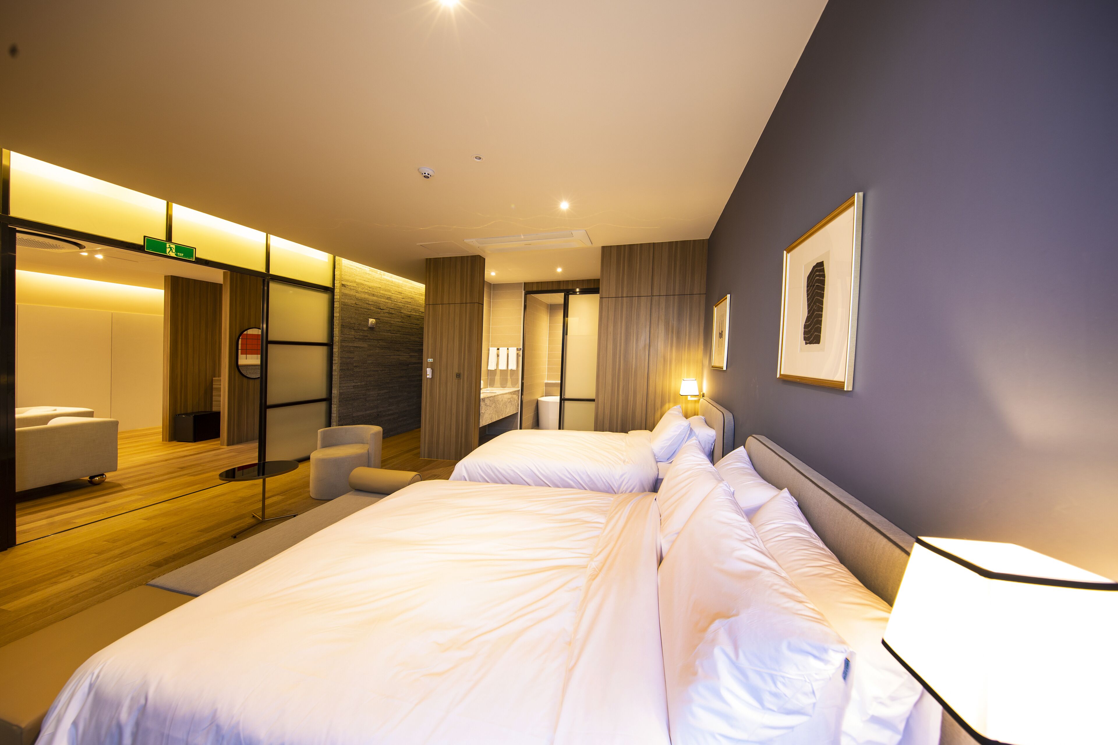 Une chambre d’hôtel moderne avec deux lits, un coin salon et une salle de bain.