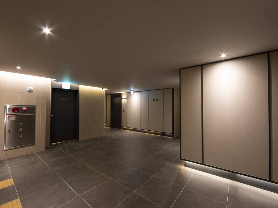A modern elevator area with a control panel, emergency button, and a door.