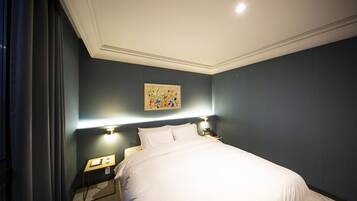 A neatly made bed in a room with dark walls, a painting on the wall, and bedside lamps.