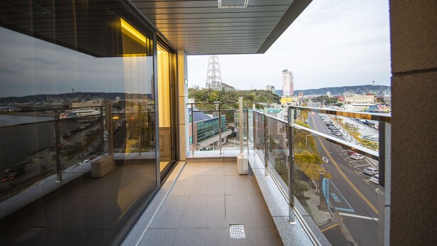 Een balkon met uitzicht op een stadsgezicht, inclusief een snelweg en gebouwen.
