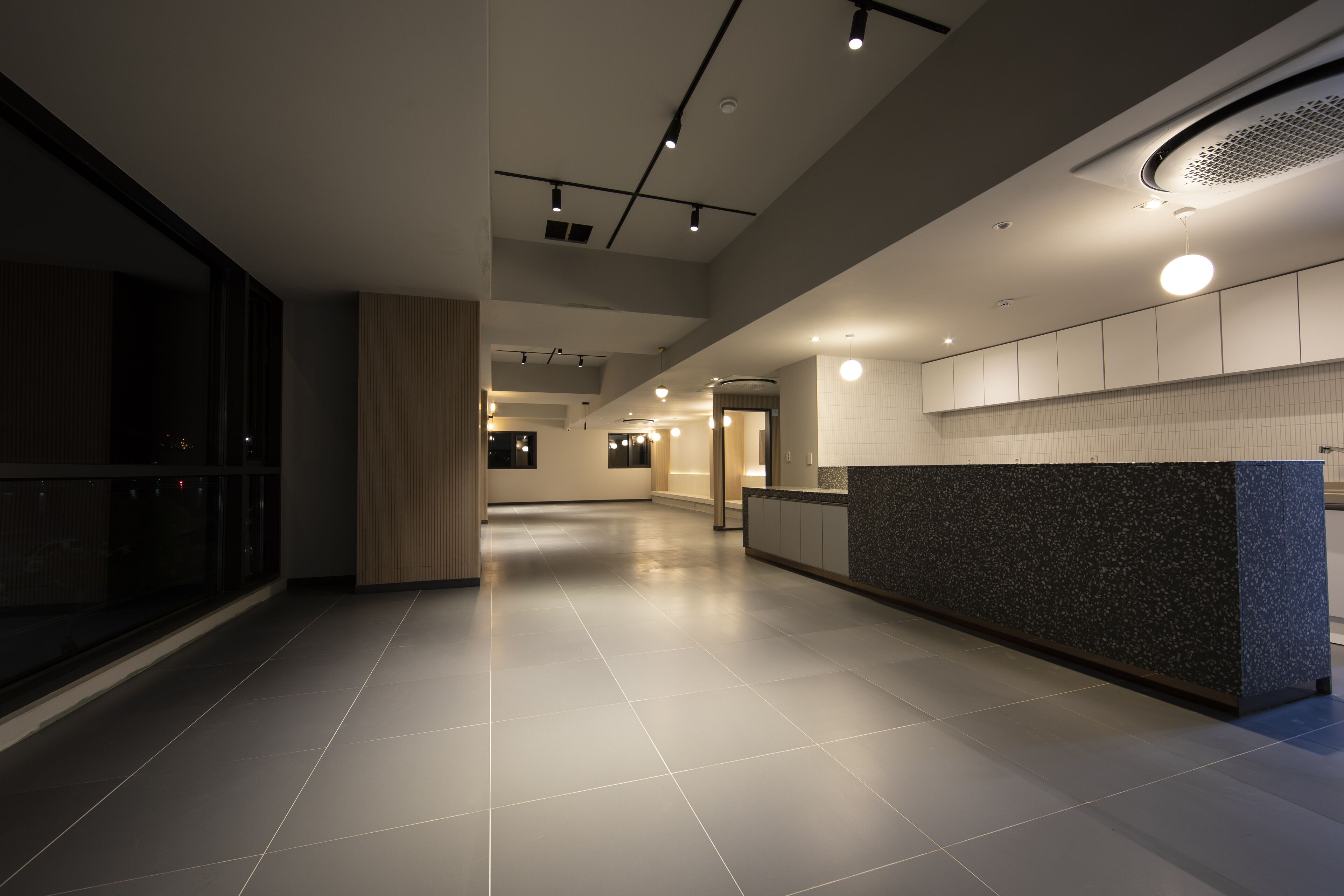 A modern hotel lobby with a reception desk, a large open space, and a high ceiling with recessed lighting.