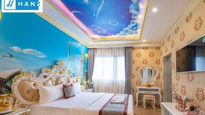 Une chambre d’hôtel luxueuse, dotée d’un grand lit, d’une décoration raffinée, d’une fresque au plafond et d’une coiffeuse avec un miroir.