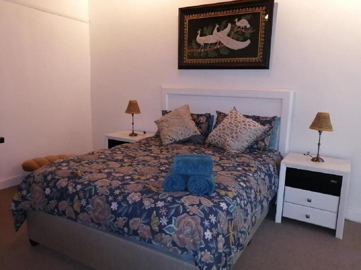 A bedroom with a floral bedspread, two nightstands with lamps, and a framed picture on the wall.