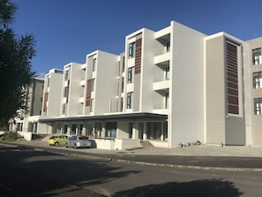 A modern multi-story building with a flat roof, large windows, and a covered entrance area.