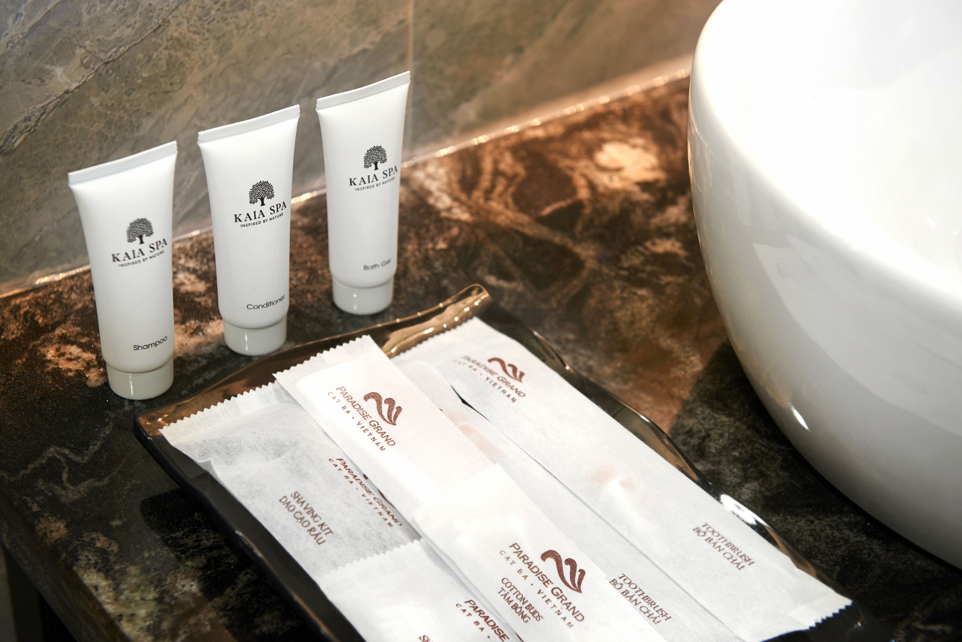 A bathroom counter with toiletries, including shampoo and conditioner tubes, and a tray with cotton pads.