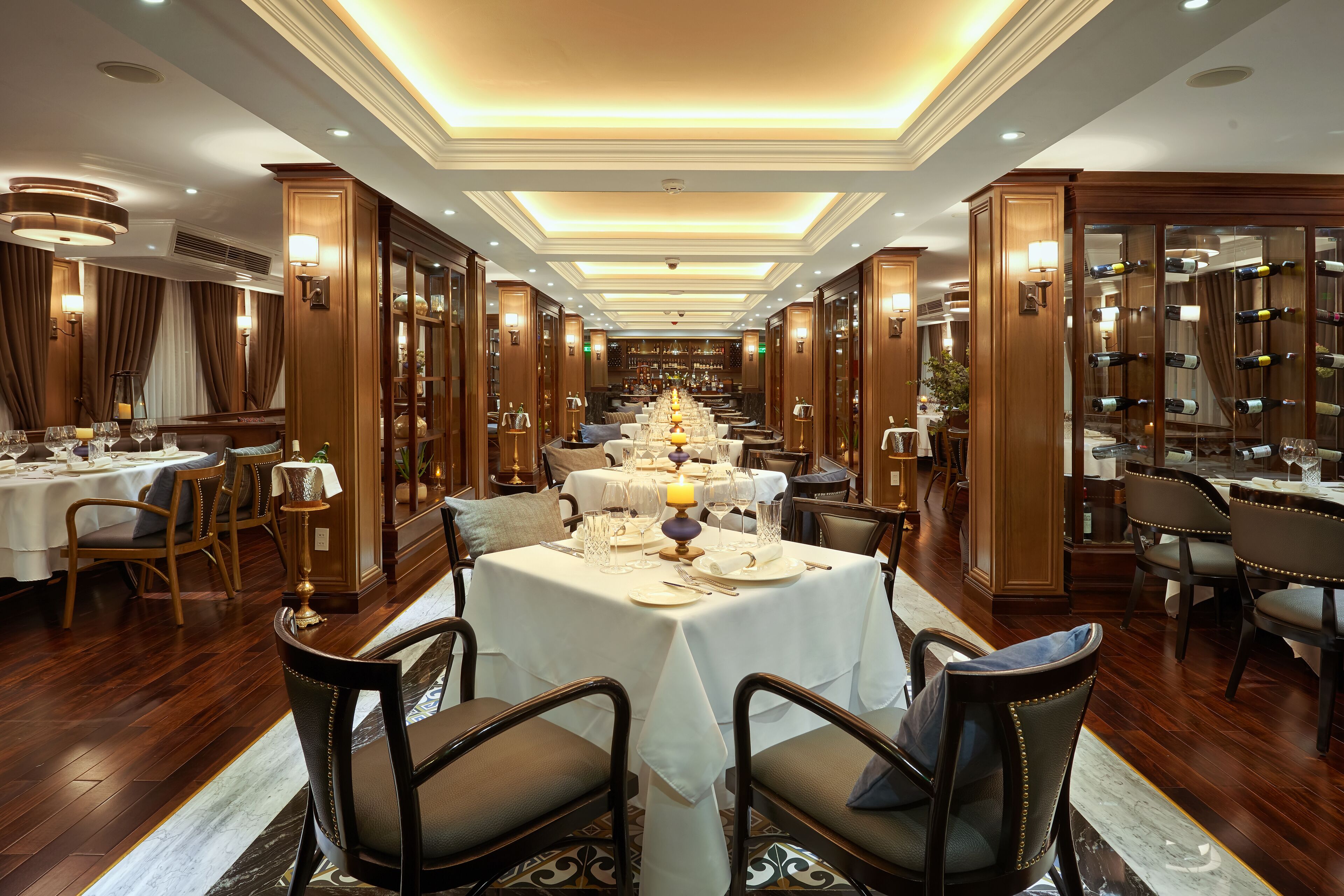 A long dining room with tables set for a meal, wooden paneling, and a chandelier.