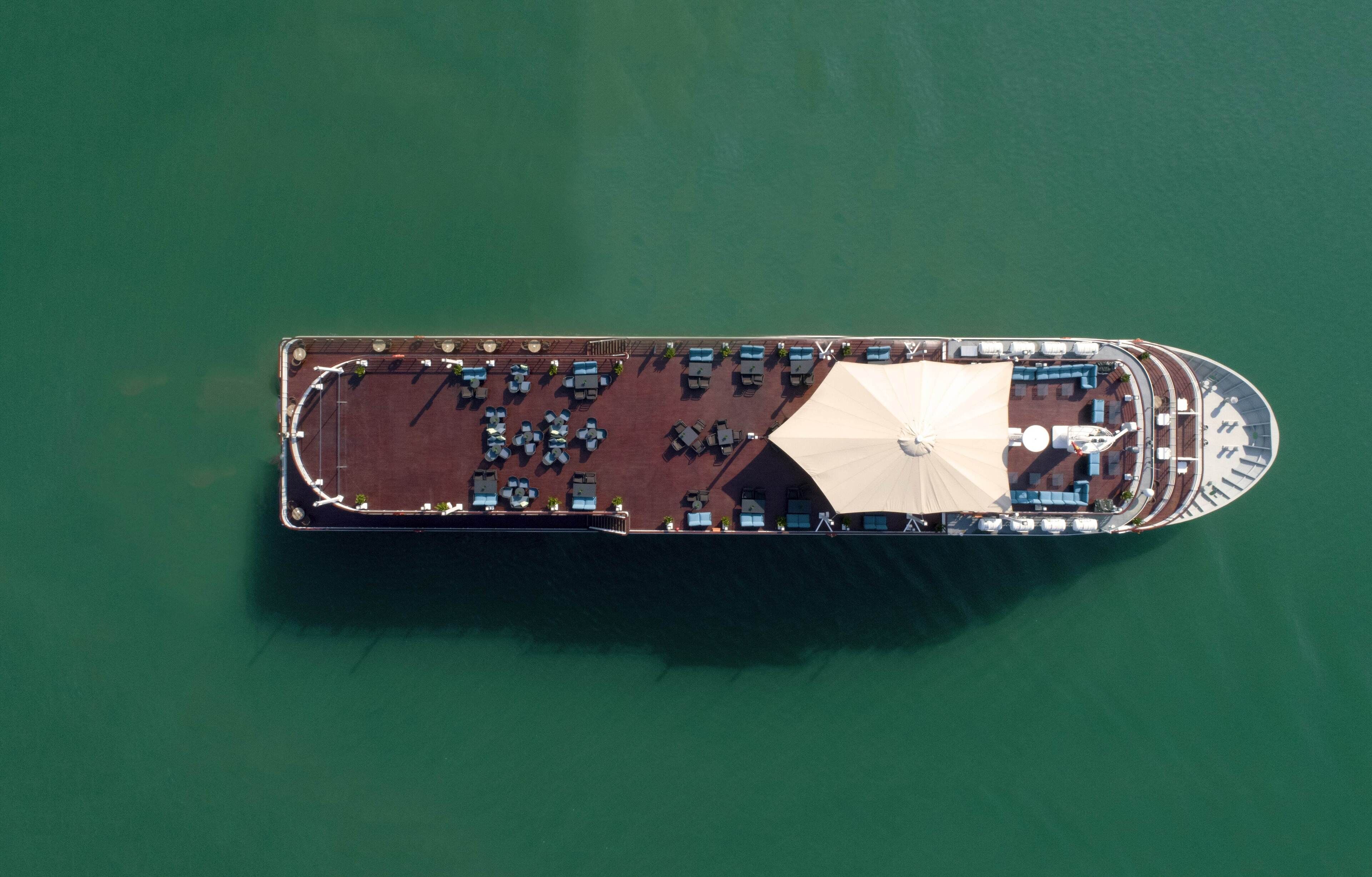 An aerial view of a cruise ship with a deck layout including seating areas and a covered section.