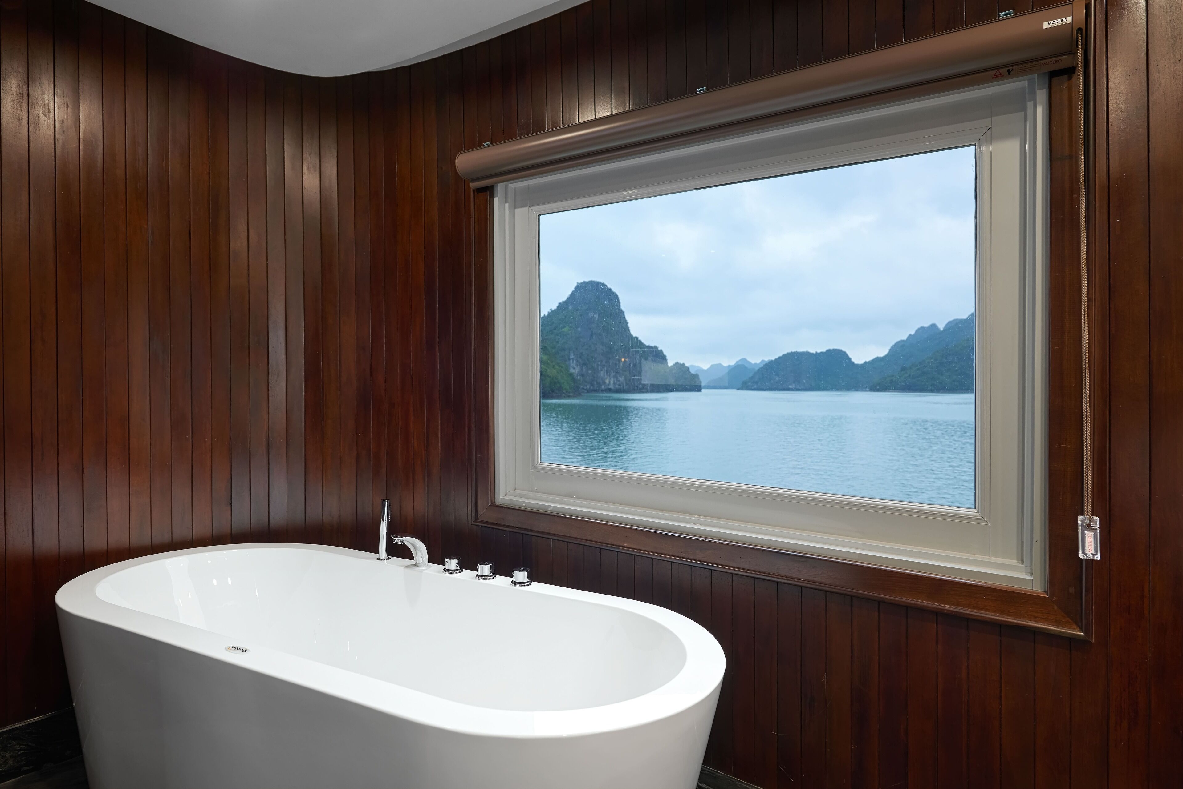 Une salle de bain avec une baignoire sur pieds, un lambris en bois et une fenêtre donnant sur un paysage montagneux.
